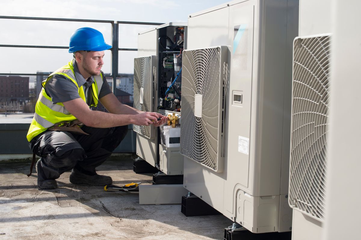 Commercial Air Conditioning Expert conducting maintenance on large outdoor compressor units